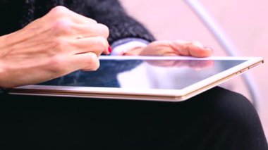 Ofis binasının dışında oturan bir iş kadını, yetişkin bir bayan patron elinde bir tablet tutuyor, mesajlar yazıyor ve internetten haber okuyor..