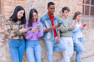 Akıllı telefonlarına bakan bir grup arkadaş kampüste interneti cep telefonuyla tarıyor.