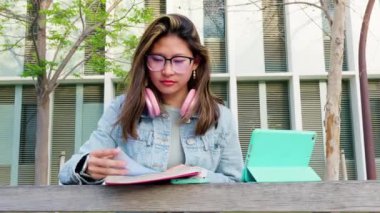 Tabletli mutlu bir öğrenci üniversite kampüsünde oturup sınavı gözden geçiriyor. üniversite hayatı