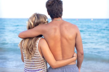 Arkadan bakınca, gülümseyen etnik çeşitlilikte bir kadın ve tatilden hoşlanan bir erkek. Güzel ve neşeli bir çift z nesli cep telefonlu bir fotoğraf için poz veriyor.