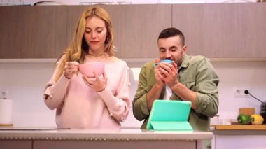 Genç bir çift tablet kullanırken gülüyor: birbirine aşık bir çift birlikte kahvaltı yapıyor ve dijital tablet kullanarak son haberleri okuyor..