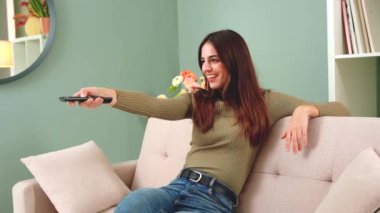 Televizyon, video ve uzaktan kumandalı bir kadın. Dairesindeki film kanalını değiştiren genç bir kadınla.