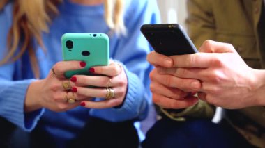 Evdeki kanepede buluşurken cep telefonlu mutlu beyaz erkek ve kadın..