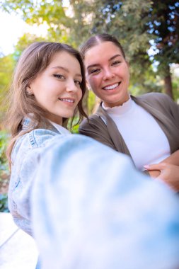İki beyaz kadın akıllı telefonuyla selfie çekiyor. Dikey.