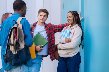 Kampüsteki müfredat notlarını incelerken konuşan ve gülen mutlu üniversite arkadaşları..