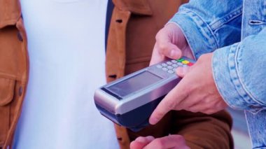 Bir kişi satış noktasında bir kart kullanarak ödeme işlemini tamamlıyor. Süreç hızlı ve kolay, modern dijital ödeme yöntemlerini günlük ortamlarda vurguluyor.