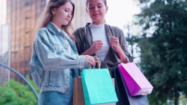  İki kadın renkli alışveriş torbalarıyla şehir merkezinde alışveriş yapmayı seviyor. Onlar hediyeler alıp dışarıda anın tadını çıkarıyorlar. Alışveriş ve perakende terapi konsepti