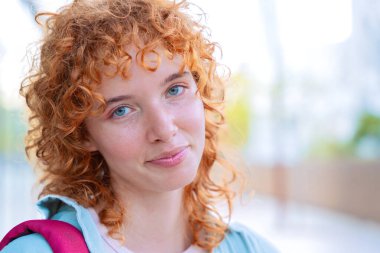  Saçları örgülü neşeli bir genç kadının yakın plan portresi. Yeşilliğin yumuşak bir arka planına sahip doğal bir ortamda, açık havada parlak bir şekilde gülümsüyor. Görüntü pozitifliği ve güveni yakalar.