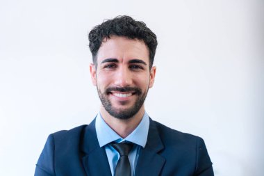 Kendine güvenen, kendine güvenen, mavi takım elbiseli ve kravatlı bir iş adamı. Sade bir arkaplanda içten bir gülümseme. Şirket, liderlik veya kariyer temaları için ideal mesleki davranış