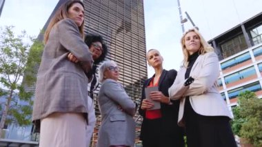 Farklı yaşlarda ve dışarıda duran kendine güvenen beş iş kadınından oluşan bir grup. Gülümseyen ve dengeli bir şekilde, modern kentsel çevrede cam binalar ile profesyonellik yayıyorlar..