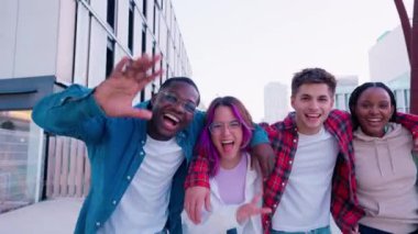  Mutlu bir grup genç arkadaş doğal bir ortamda selfie çekiyorlar. Çok çeşitliler, gülümsüyorlar ve kameraya el sallıyorlar. Güneşli gökyüzünün altında neşe ve dostluk saçıyorlar.. 