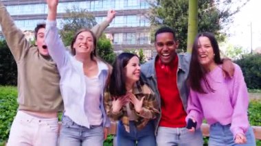  Grup Neşeli bir grup genç arkadaş dışarıda bir arada duruyorlar, gülümsüyorlar, gülüyorlar ve park ortamında eğleniyorlar..