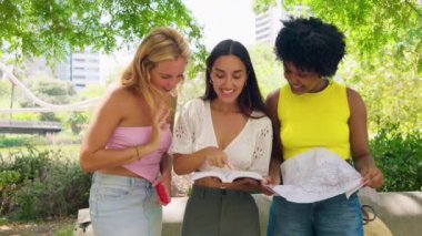 Üç neşeli kadından oluşan bir grup, açık hava ortamında gezmek ve gülümsemek için bir harita kullanıyor. Yolculuk, macera ve dostluk temaları için mükemmel. Canlı ve güneşli yaz atmosferleri..