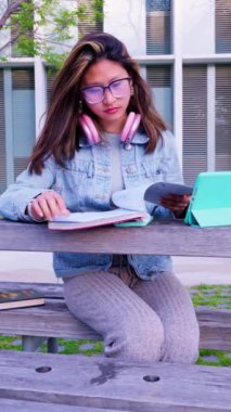 Tabletli mutlu bir öğrenci üniversite kampüsünde oturup sınavı gözden geçiriyor. üniversite hayatı