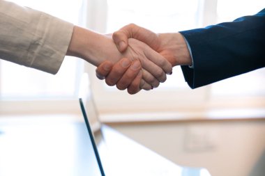 Close-UClose-up of a professional handshake between two people wearing business attire, symbolizing partnership, agreement, or collaboration in an office setting clipart