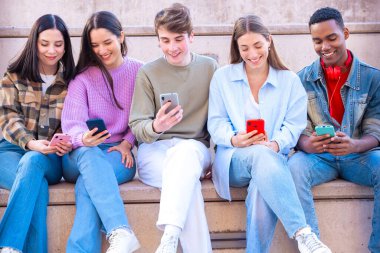 Akıllı telefonlarına bakan bir grup arkadaş kampüste interneti cep telefonuyla tarıyor.