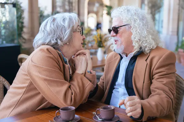 Kafkas 'lı mutlu çift açık hava kafeteryasında romantik bir anı paylaşıyor. Güneşli bir günde sıcak ve sevgi dolu bir atmosferde gülümsemek, el ele tutuşmak ve kahvenin tadını çıkarmak. 