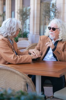 Kafkasyalı son sınıf çifti, açık hava kafeteryasında el ele tutuşuyor. Kahverengi ceketler içinde duygusal bir anı paylaşıyorlar. Aşk kavramı, bağlantı, olgunluk ve barışçıl yaşam tarzı. Dikey