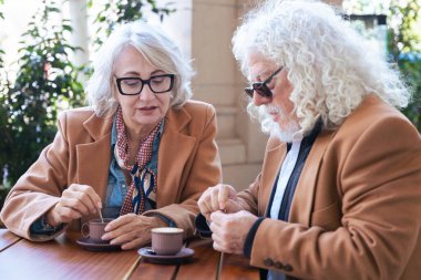 Kafkasyalı son sınıf çifti açık bir kafede kahve içiyor. Kadın, adamla samimi ve düşünceli bir an yaratarak yakın bir şekilde konuşuyor. Bağlantı, güven ve paylaşılan deneyimler kavramı. 