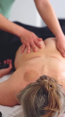 Profesyonel masaj terapisti temiz, parlak bir spa odasında sırt masajı yapıyor. Müşteri yüzüstü masada yatıyor. Sağlık, terapi, rahatlama ve vücut bakımı konuları için mükemmel..