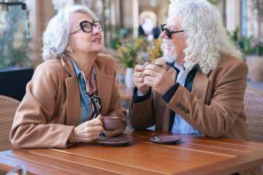 Kafkasyalı son sınıf çifti açık bir kafede kahve içiyor. Kadın, adamla samimi ve düşünceli bir an yaratarak yakın bir şekilde konuşuyor. Bağlantı, güven ve paylaşılan deneyimler kavramı. 