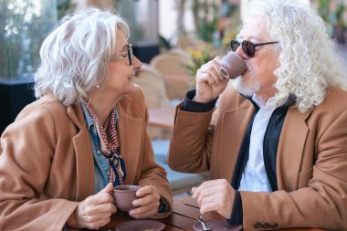 Kafkasyalı son sınıf çifti açık bir kafede kahve içiyor. Kadın, adamla samimi ve düşünceli bir an yaratarak yakın bir şekilde konuşuyor. Bağlantı, güven ve paylaşılan deneyimler kavramı. 