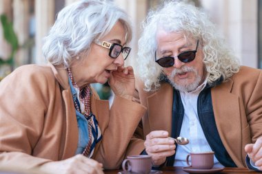 Kafkasyalı son sınıf çifti açık bir kafede kahve içiyor. Kadın, adamla samimi ve düşünceli bir an yaratarak yakın bir şekilde konuşuyor. Bağlantı, güven ve paylaşılan deneyimler kavramı. 