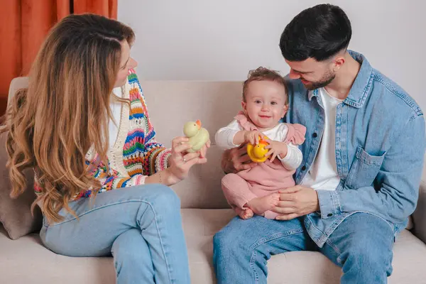 Gülümseyen ebeveynler kanepede otururken oyuncak tutan kızlarıyla oyun oynamaktan hoşlanırlar. Sıcak bir yuva ortamında sevgi, renk ve sıcaklıkla dolu neşeli bir aile bağlılık anı.. 