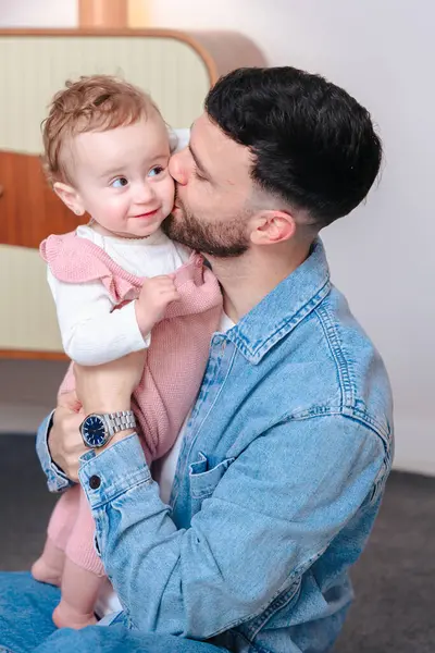 Dikey Portre Genç Baba kızını sıcak ve rahat bir evde tutarken öpüyor. Şefkatle, sevgiyle ve evde babacan sevgiyle dolu bir aile anı.. 