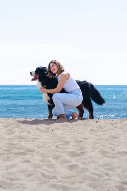 Kumsalda köpeğinin yanında diz çökmüş neşeli genç bir kadının portresi. Güneşli bir günde her ikisi de kameraya bakar, deniz kenarında huzurlu bir anın keyfini çıkarırlar neşe, dostluk ve doğa ile. Dikey