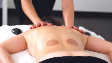 Profesyonel masaj terapisti, temiz, parlak bir spa odasında sırt masajı yapıyor. Müşteri yüzüstü masada yatıyor. Sağlık, terapi, rahatlama ve vücut bakımı konuları için mükemmel.