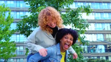  İki mutlu arkadaş, bir Afrikalı Amerikalı ve bir Kafkasyalı, bir şehir parkında sırtına binmiş, kolları açık gülüyorlar, arkalarında cam binalar yükseliyor, özgürlüğü ve arkadaşlığı kutluyorlar.