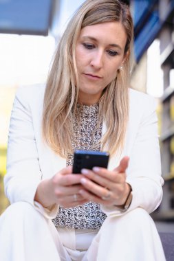 Bej ceketli neşeli bir adamın portresi gülümserken kırmızı bir akıllı telefonu canlı mavi arka plan, teknoloji, iletişim ve modern yaşam tarzını dikey biçimde kullanıyordu.