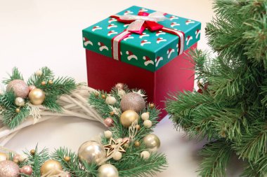 Yılbaşı hediyesi, Noel çelengi ve beyaz arka planda Noel ağacı. Kırmızı kurdeleli Noel hediyesi kutusu. Tatil konsepti. Noel konsepti. Yüksek kaliteli fotoğraf.