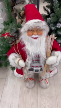 Geleneksel bir Noel Baba heykelciğinin yakın çekimi. Kürklü bir şapkası var. Etrafı şenlikli süslemelerle çevrili. Yüksek kalite 4k görüntü