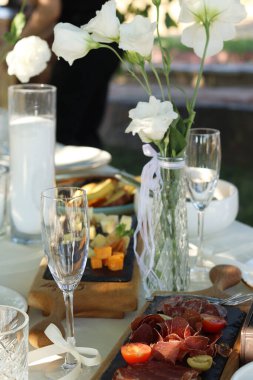 Bahçede sevgili bir çift için şık bir düğün ya da bekarlığa veda partisi. Taze ranunculi çiçekli güzel bir dekor. Gurme peynir tahtası. Pankart. Yüksek kalite fotoğraf