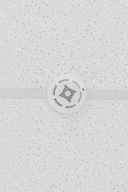 Dairenin tavanında yangın alarmı ve acil durum alarmı var. Beyaz arka planda asılı duran tavana moke dedektörü monte edildi. Yüksek kalite fotoğraf