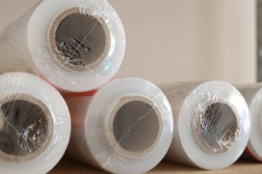 Plastiğe sarılı birkaç rulo temiz film. Yüzeyde yatarlar, karton çekirdekleri ön planda görünür. Yakın plan. Yüksek kalite fotoğraf