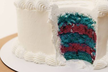 Kremalı beyaz pasta. Pastadan turkuaz ve pembe pandispanya tabakalarını gösteren bir parça kesilmiş. Kapatın. Bekleme partisi. Yüksek kalite fotoğraf