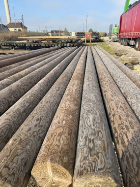 Görünür tahıl dokusuna sahip ahşap elektrik direklerini kapatın, bir sanayi bölgesinde depolanmış, elektrik veya haberleşme altyapısına yerleştirilmeye hazır. Yüksek kalite fotoğraf