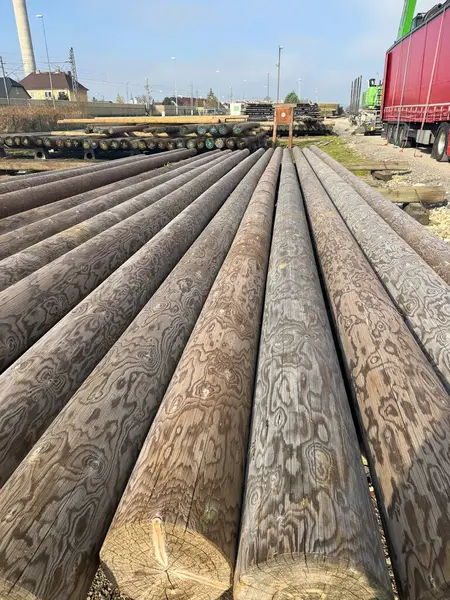 Görünür tahıl dokusuna sahip ahşap elektrik direklerini kapatın, bir sanayi bölgesinde depolanmış, elektrik veya haberleşme altyapısına yerleştirilmeye hazır. Yüksek kalite fotoğraf