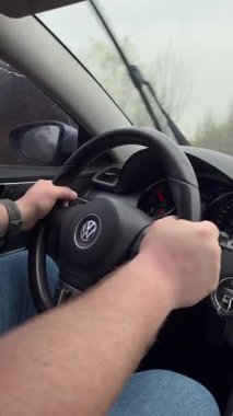 Uzhhorod, Ukrayna -5 Nisan 2025. Bir adam yolda Volkswagen araba kullanıyor. Yağmurlu havada direksiyon başında, camda hareket eden silecekleri olan bir şoför.