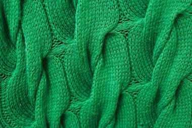 Kablo desenli yeşil örülmüş yün kumaşın yakın çekim dokusu. Samimi ve sıcak tekstil arka planı, moda, kış giysileri, el işi ve tasarım gibi konular için idealdir..