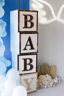 Bebek için dekoratif bebek partisi düzeneği yığılmış mektup blokları, beyaz balonlar, altın yapraklar ve melek kanatlı neon ışıklar. Afiş için mükemmel bir yer ve metin için de yer var. Yüksek kalite fotoğraf