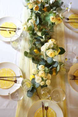 Çiçek aranjmanları ve tabakta turunçgil dilimleri olan limon temalı şık bir masa manzarası. Yaz kahvaltıları, bahçe partileri ya da samimi kutlamalar için mükemmel bir düzen.