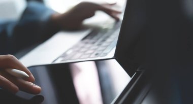 İşletme ve Finans. Ofiste dijital tablet ve dizüstü bilgisayar kullanan bir iş adamı. İşadamı çalışıyor, tablet ekranda dokunuyor ve dizüstü bilgisayarda yazıyor, iş verilerini araştırıyor, sörf yapıyor. 