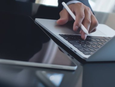 İşletme ve Finans. Ofiste dijital tablet ve dizüstü bilgisayar kullanan bir iş adamı. İşadamı çalışıyor, tablet ekranda dokunuyor ve dizüstü bilgisayarda yazıyor, iş verilerini araştırıyor, sörf yapıyor. 