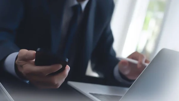 İşletme ve Finans. Ofiste dijital tablet ve dizüstü bilgisayar kullanan bir iş adamı. İşadamı çalışıyor, tablet ekranda dokunuyor ve dizüstü bilgisayarda yazıyor, iş verilerini araştırıyor, sörf yapıyor. 