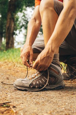 Dağda ayakkabı bağcıkları bağlayan yürüyüşçü.