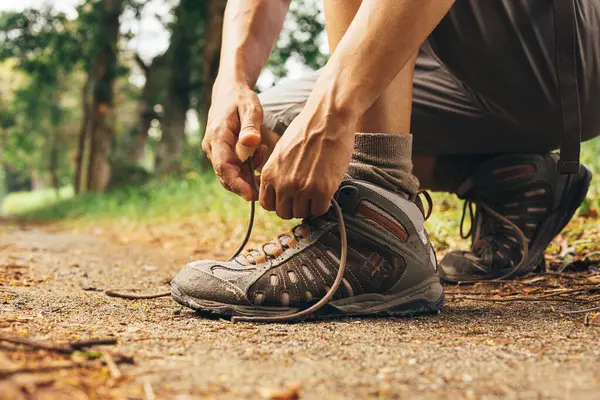 Dağda ayakkabı bağcıkları bağlayan yürüyüşçü.